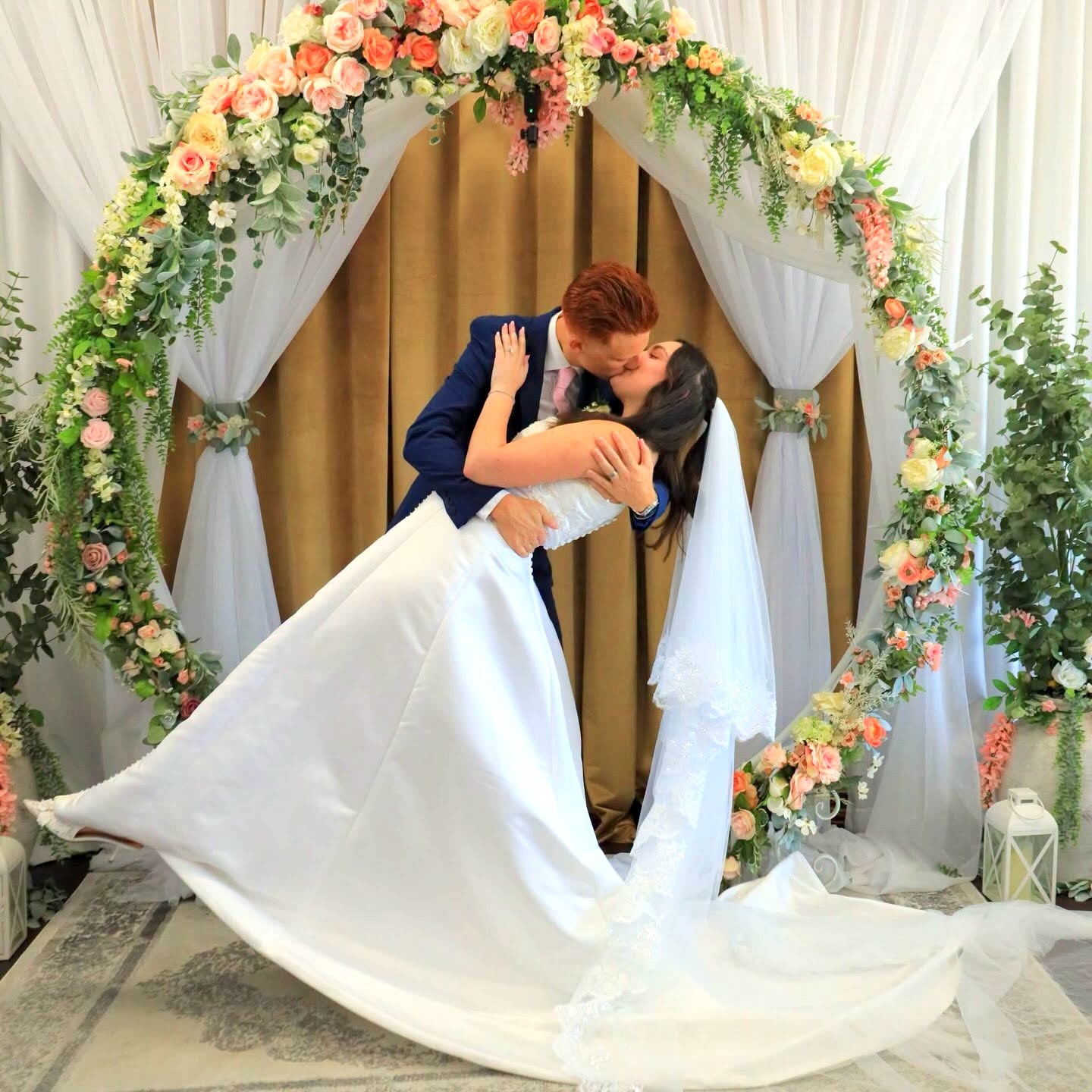 Bride and groom kissing beneath the floral arch at Grand Entrance Wedding Chapel