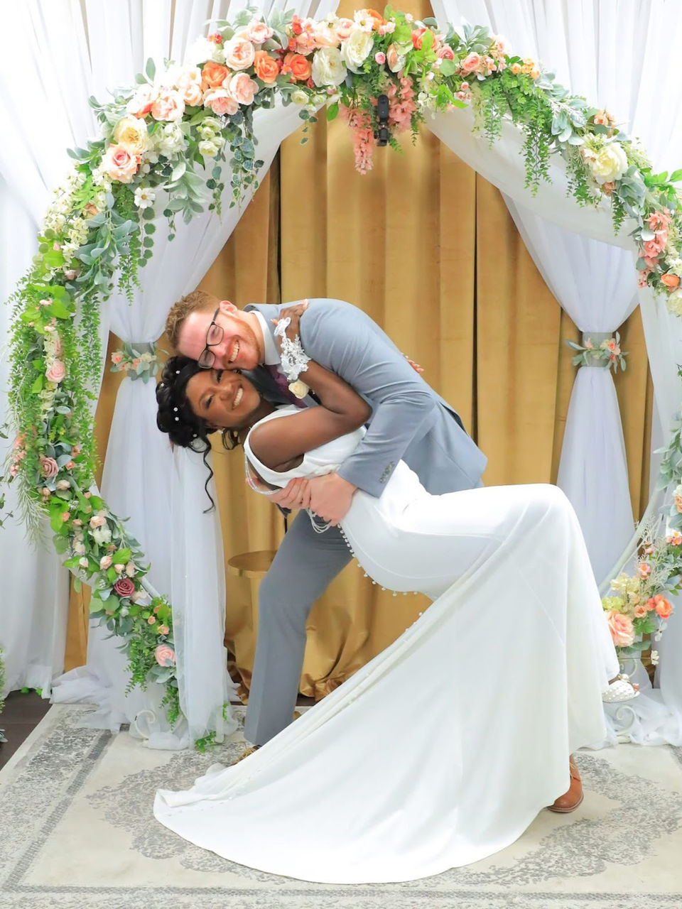 Newly married couple celebrating beneath the floral arch at Grand Entrance