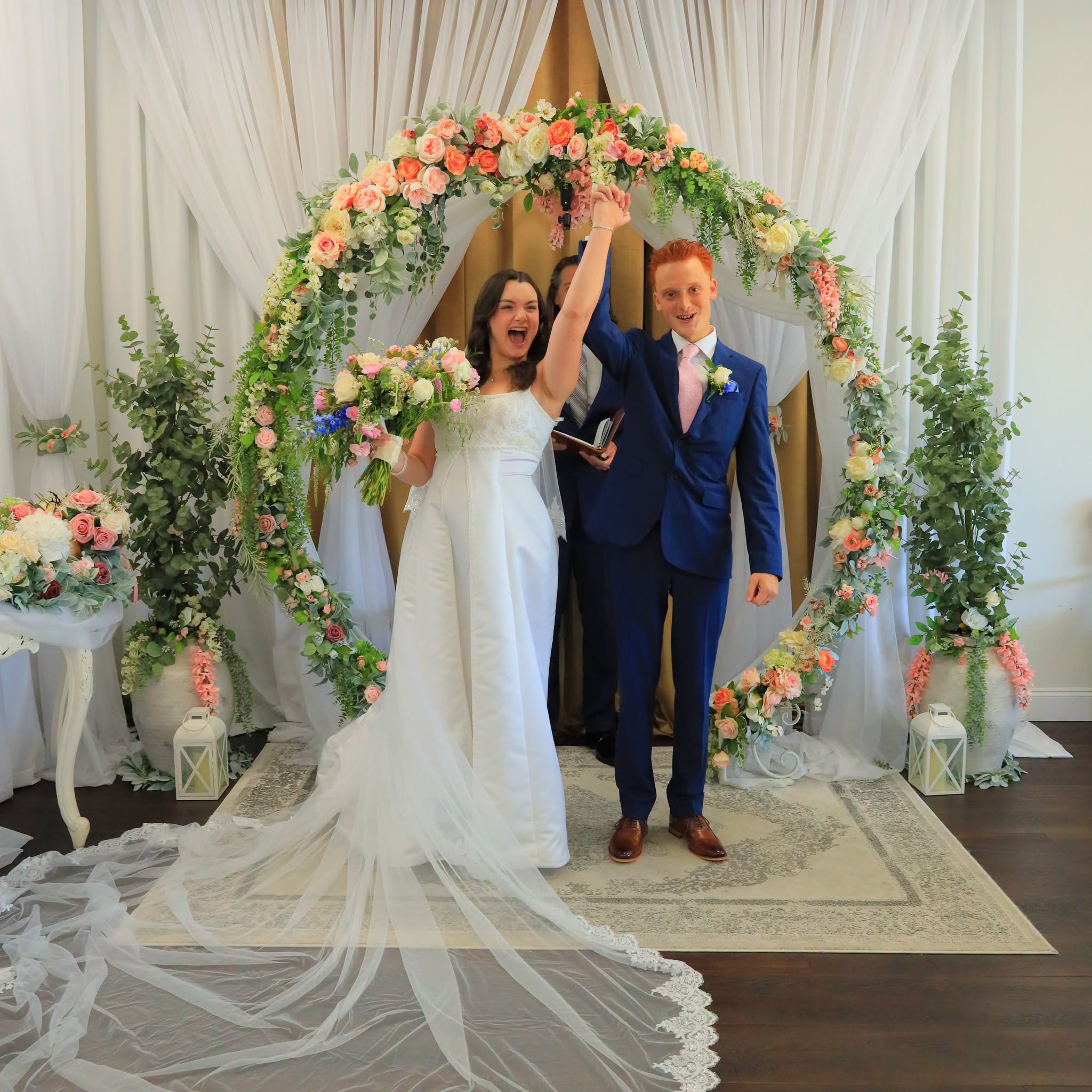 Newly married couple celebrating beneath the floral arch at Grand Entrance Wedding Chapel